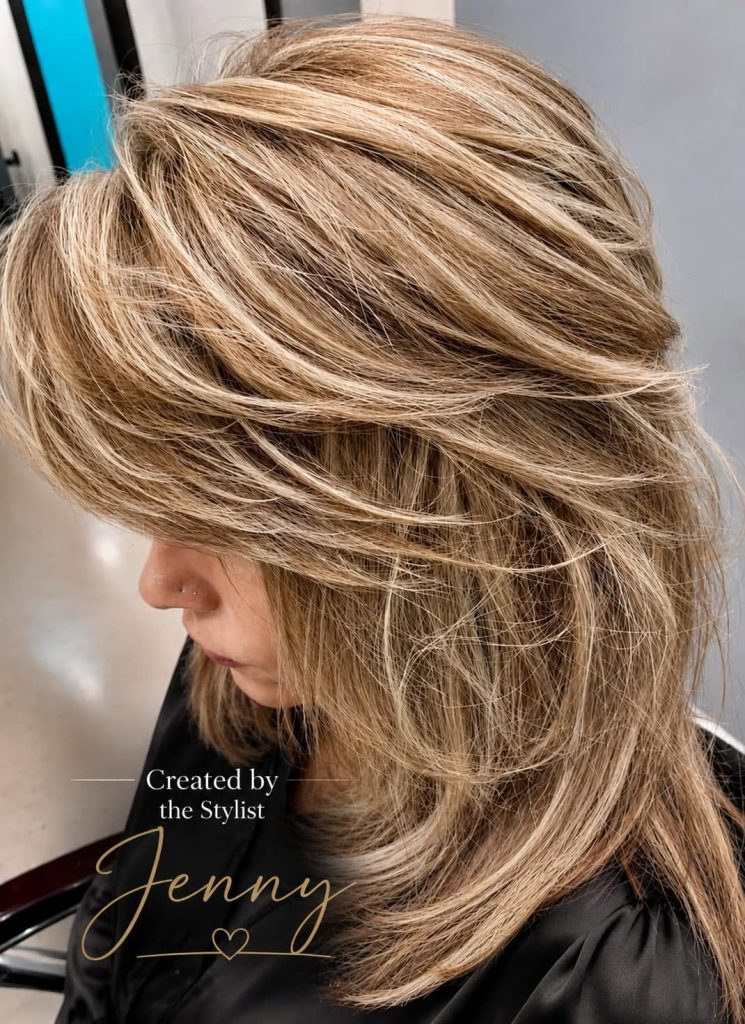 Side profile of a woman with layered, voluminous blonde hair; text reads “Created by the Stylist Jenny.”